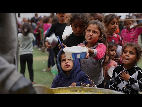 Palestinianos esperam na fila por comida em cozinha de caridade em Gaza
