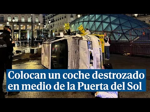Greenpeace coloca un coche destrozado en la Puerta del Sol en protesta por los combustibles fósiles