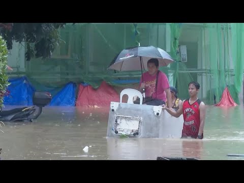 Residents wade through floodwaters in Rizal province, Philippines in wake of Tropical Storm Yagi