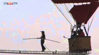 فيديو..مغامر مجنون يمشي على حبل مثبت بين منطادين بالسماء