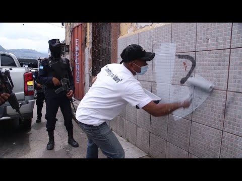 Policía de Honduras escolta a presos mientras estos pintan paredes que habían sido pintadas con graf