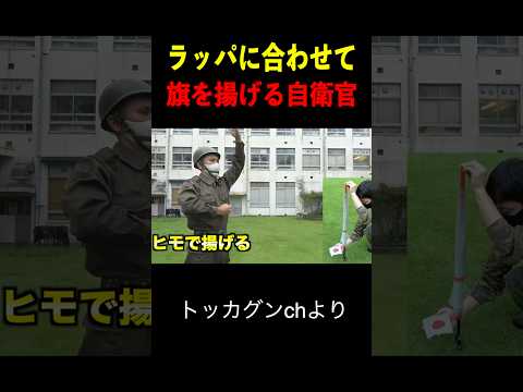 ラッパに合わせて旗を揚げる自衛官