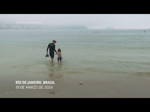 Una niña y su padre bucean para remover  basura en las aguas de las playas de Río de Janeiro