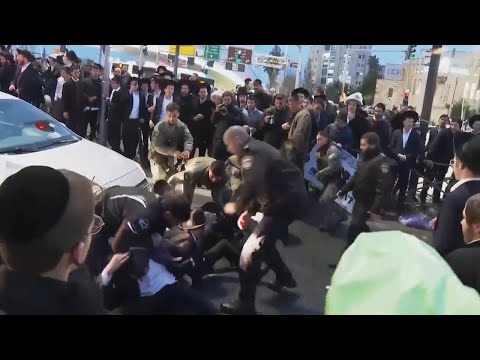 Dozens of ultra-Orthodox protesters block Jerusalem road during a demonstration over a potential new