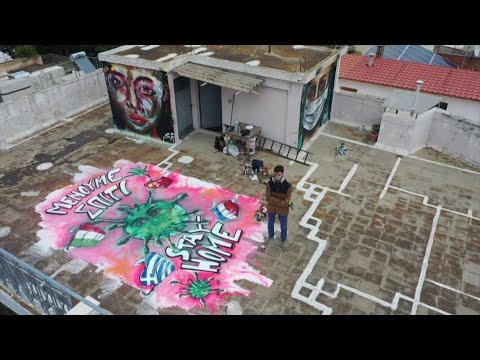 À Athènes, un graffeur peint une fresque inspirée du coronavirus sur le toit de son immeuble