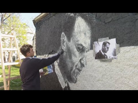 Artists spray-paint portraits of Alexei Navalny behind a Soviet monument in Vienna