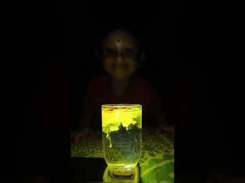 yellow viral sparkle falling in water glass, mobile flash light
