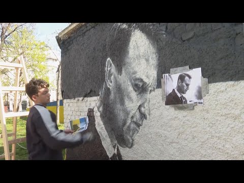 Artists spray-paint portraits of Alexei Navalny behind a Soviet monument in Vienna